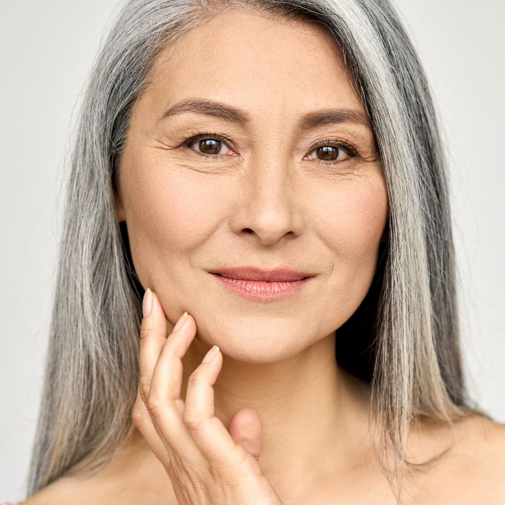 Grey hair lady using aging skin collection beauty products